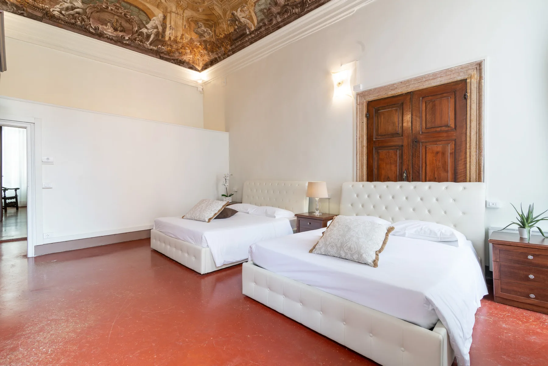 Un dormitorio con dos camas bajo un techo pintado y ornamentado.