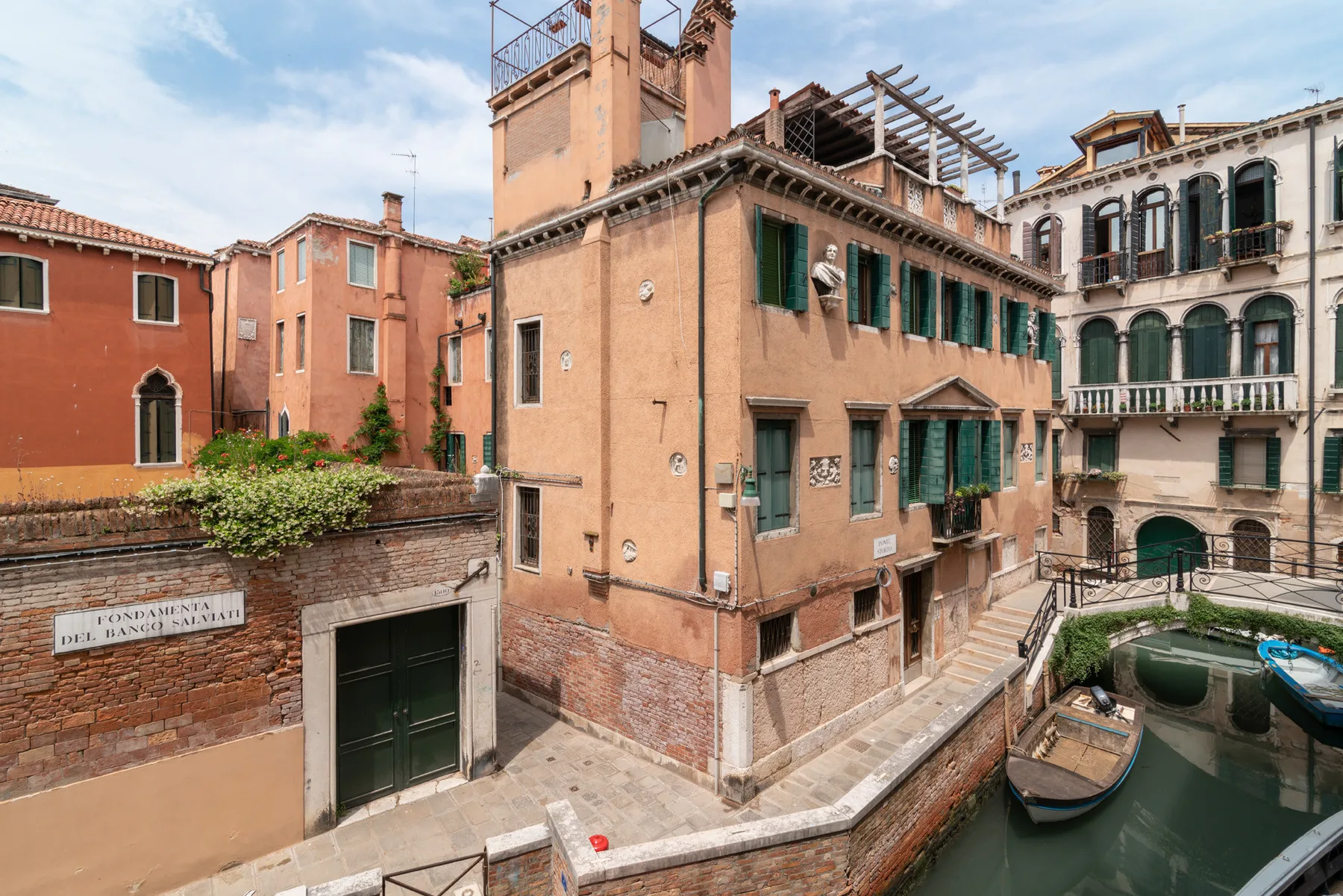 Escena junto a un canal, con edificios históricos y una pequeña embarcación.