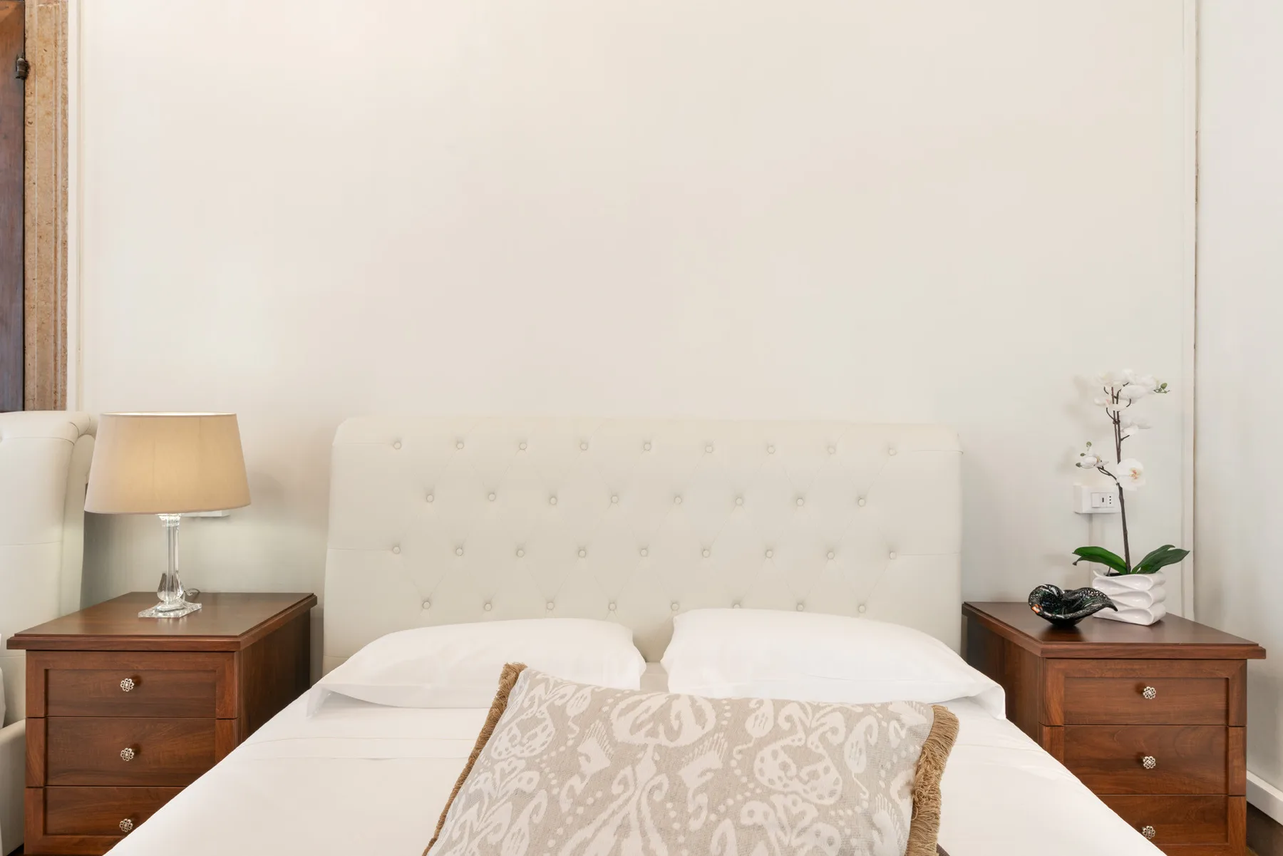 Un dormitorio con una cama entre dos mesitas de noche de madera.