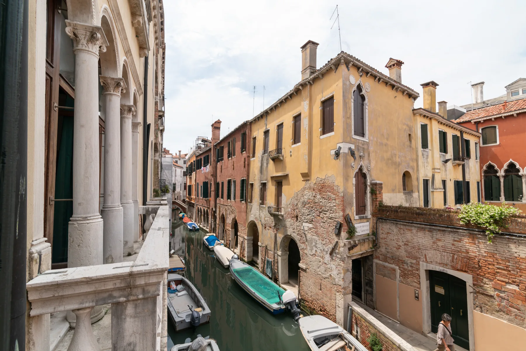 Un canal estrecho pasa entre edificios históricos, con varias embarcaciones en el agua.