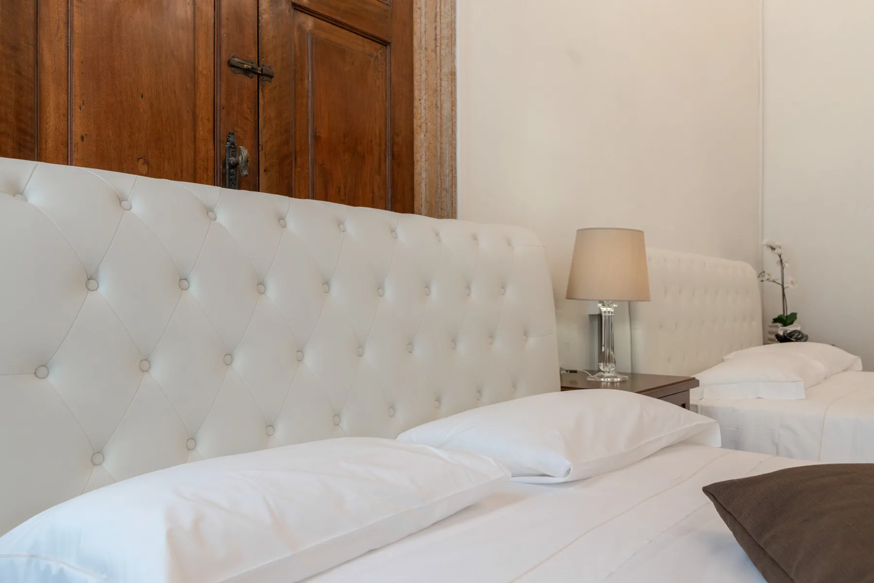 Un dormitorio con camas blancas y una lámpara de noche.