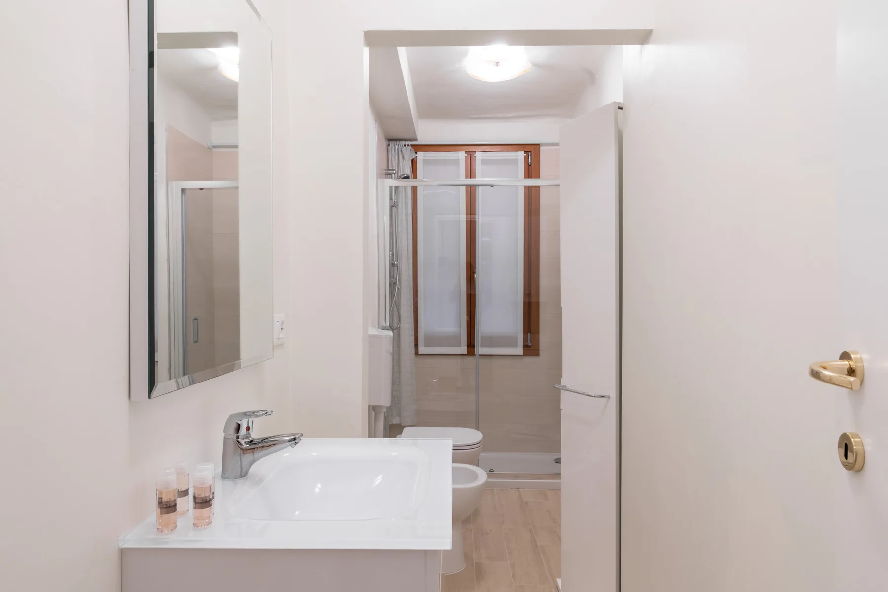 Un baño con lavabo y una zona de ducha al fondo.