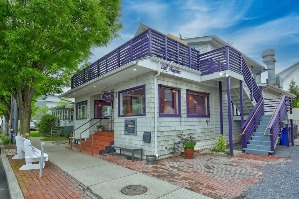 A street-facing building has a purple-railed upper deck and an outdoor staircase.