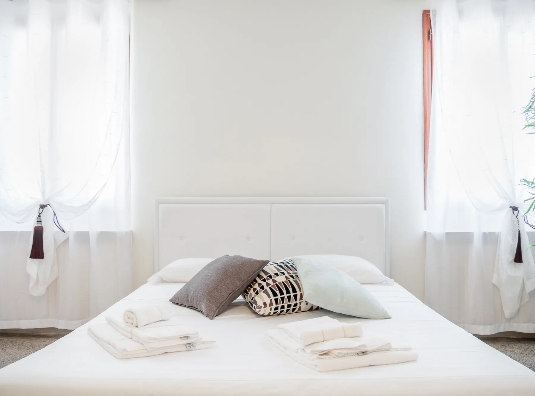 A bright bedroom with a neatly made bed and folded towels.