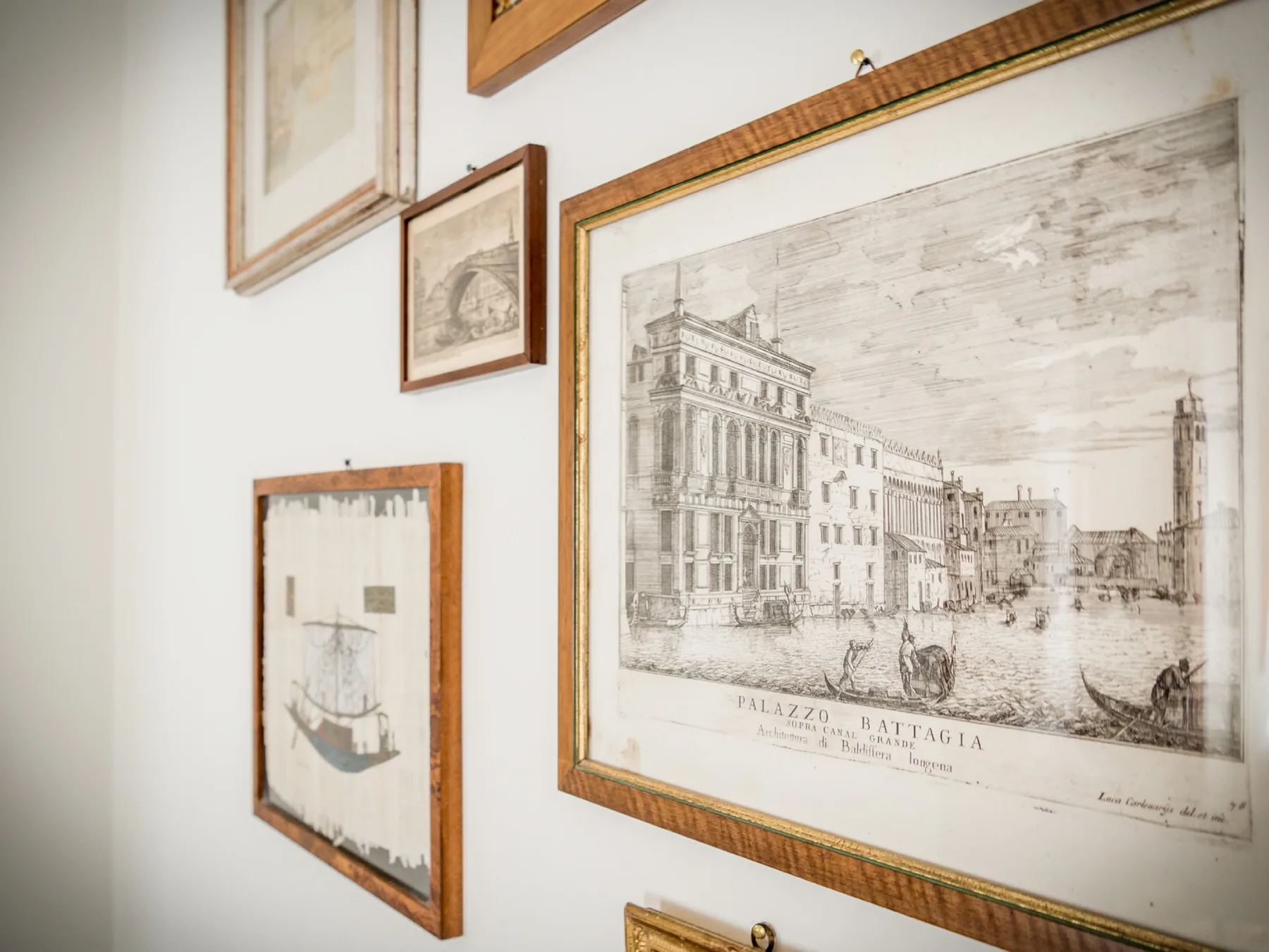Framed prints and drawings hang together on a white wall.