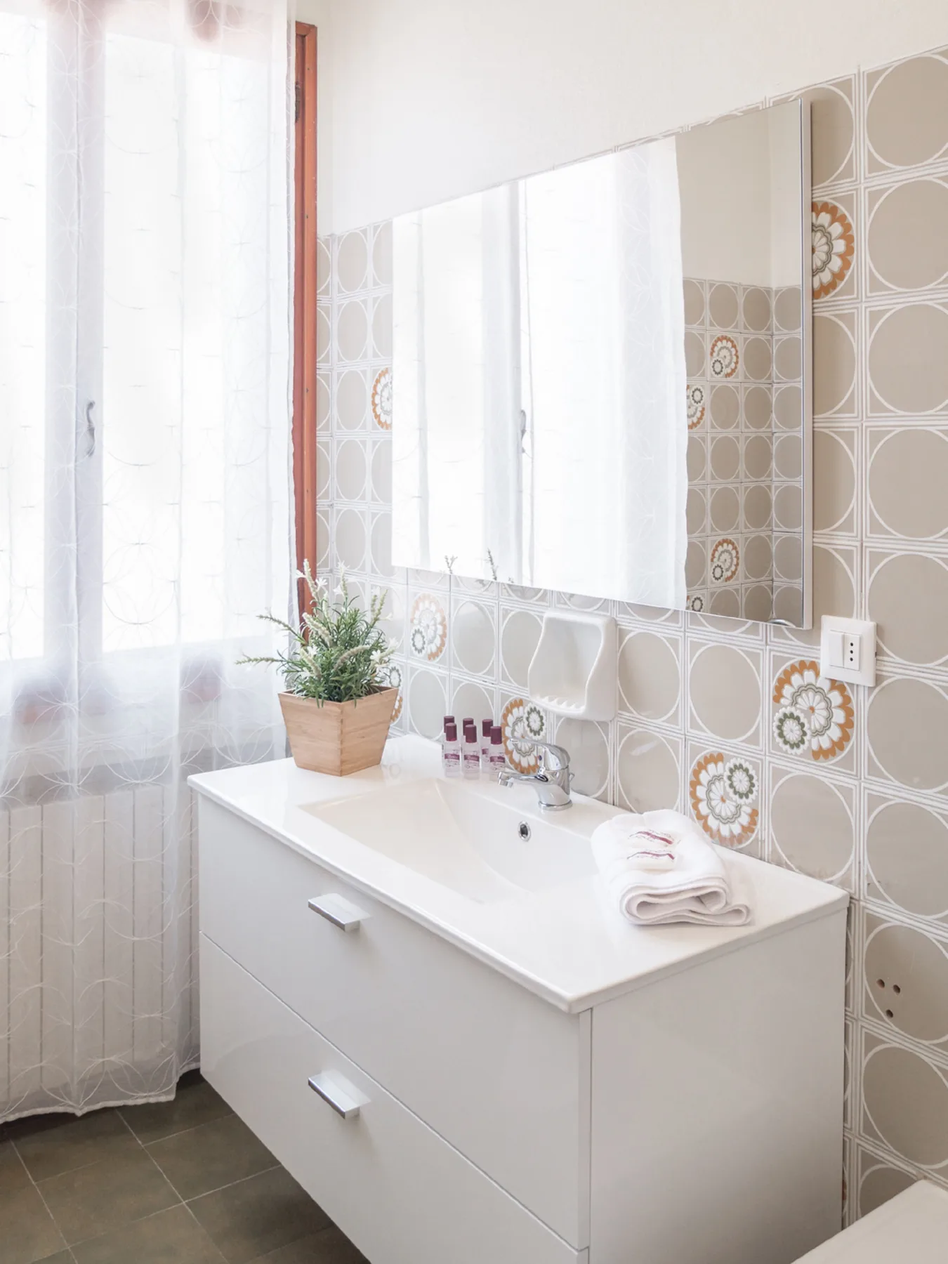 A bright bathroom vanity with a wide mirror and a potted plant.