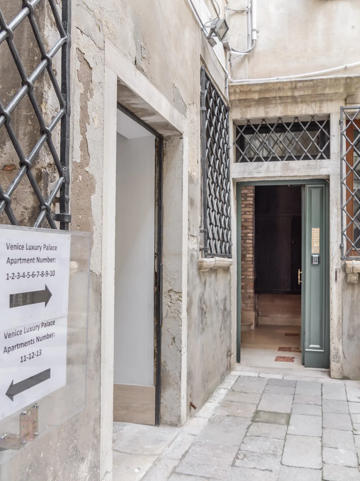 A stone-paved passage with doorways and metal lattice grilles.