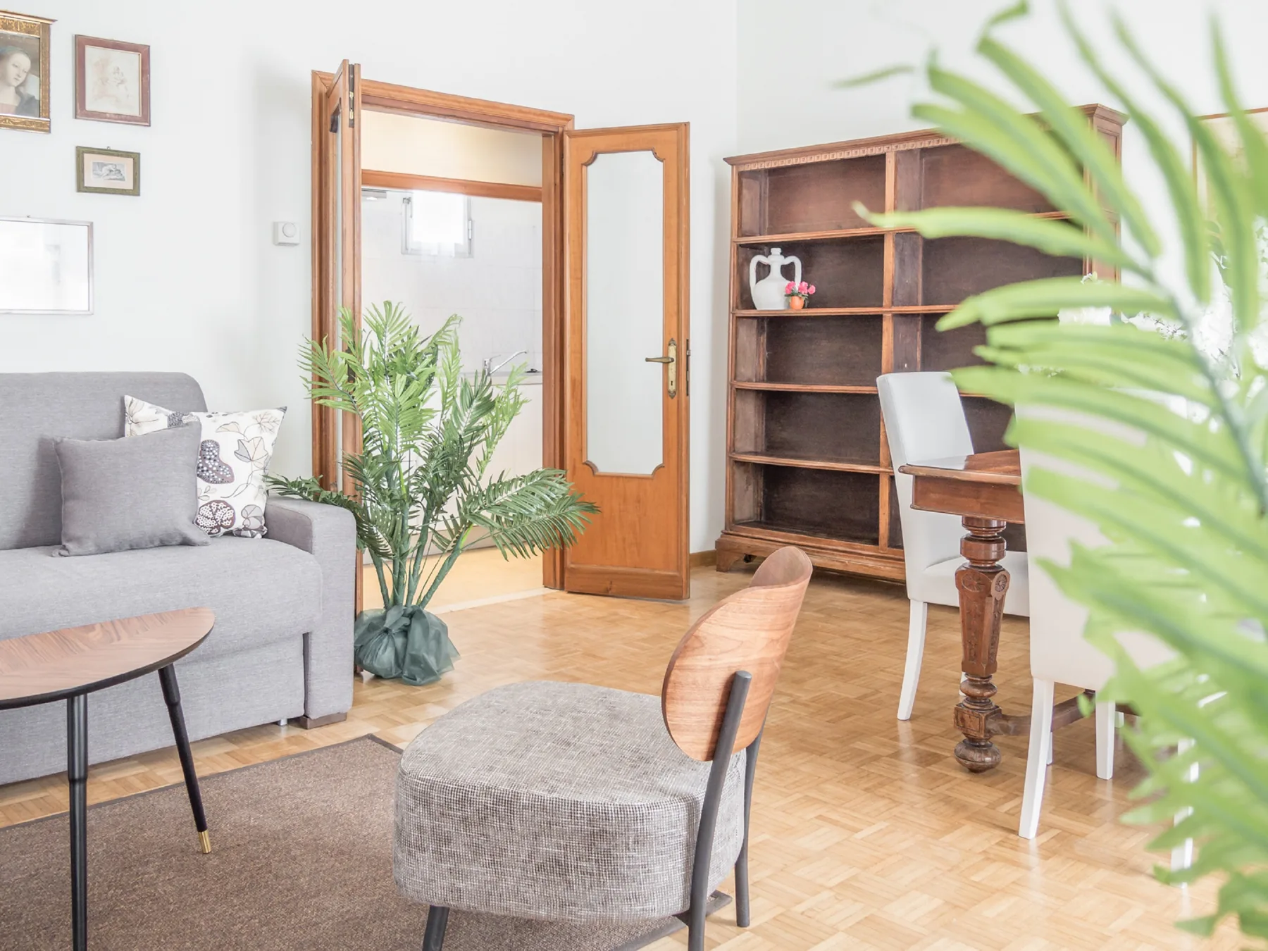 A bright living room with seating, a wooden desk, and an open doorway.
