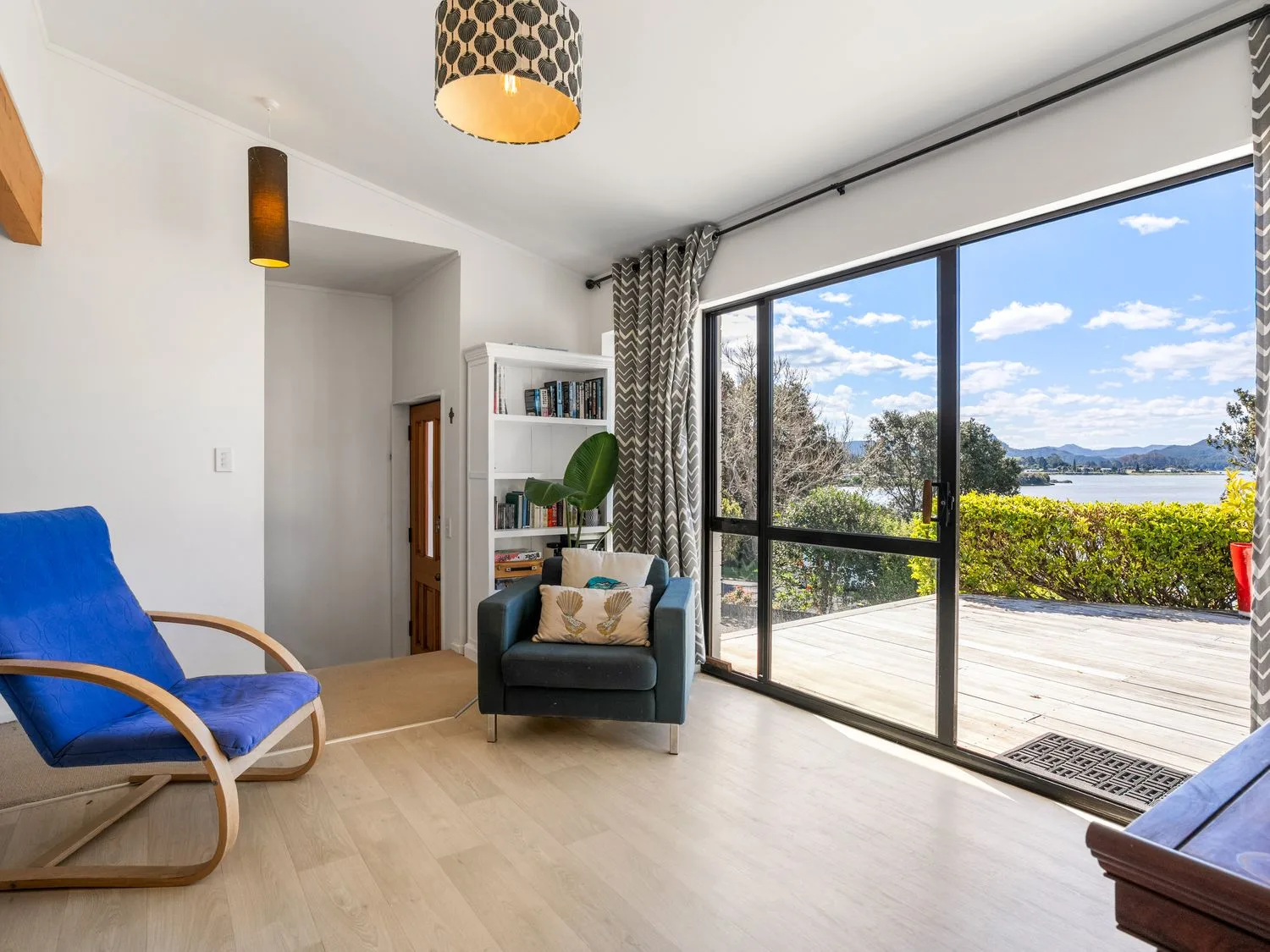 A living room with a rocking chair and a sofa at Harbour house - Whangamata Holiday Home