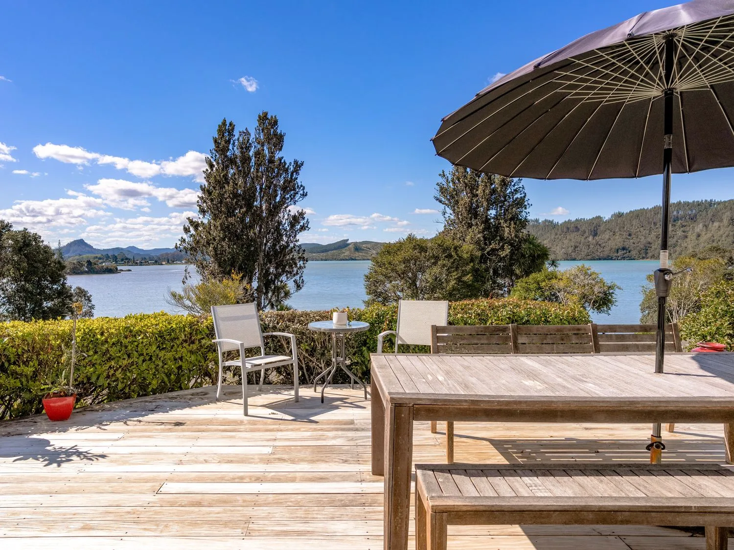 An outdoor seating area with a table and chairs at Harbour house - Whangamata Holiday Home