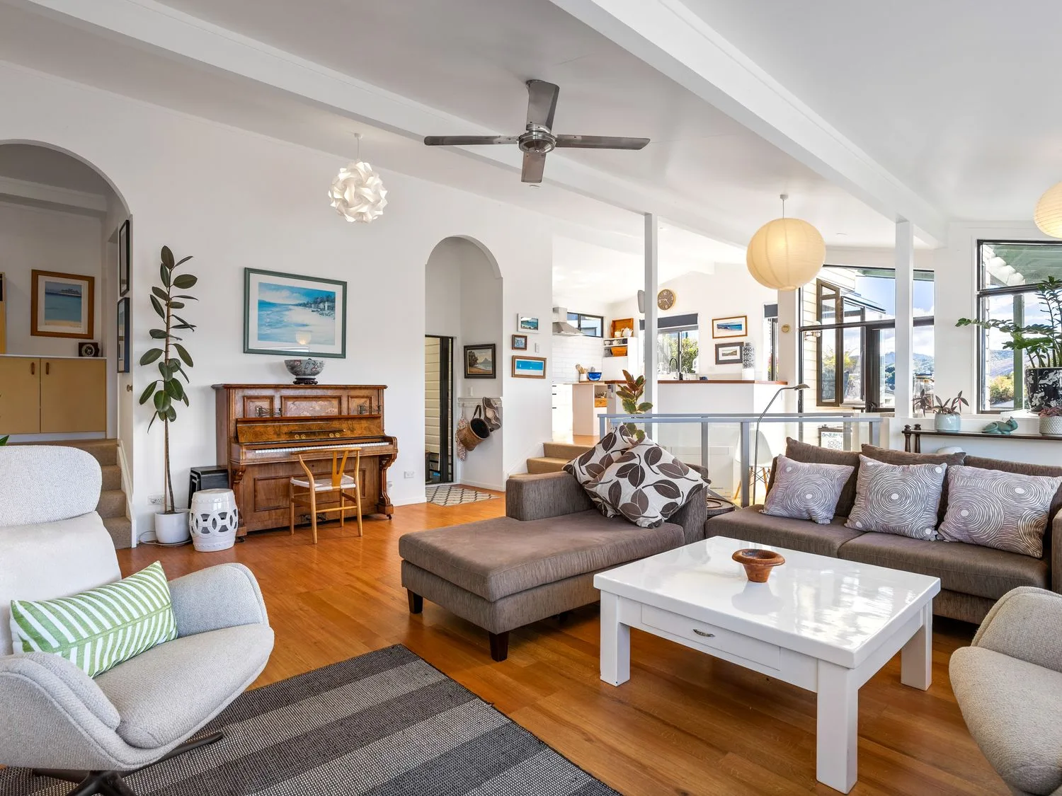 A living room with a piano and seating area at Harbour house - Whangamata Holiday Home