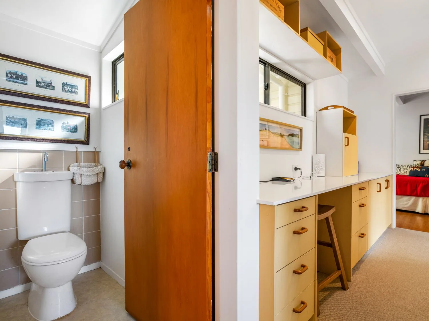 A bathroom with a toilet is visible beside a long counter and cabinetry.