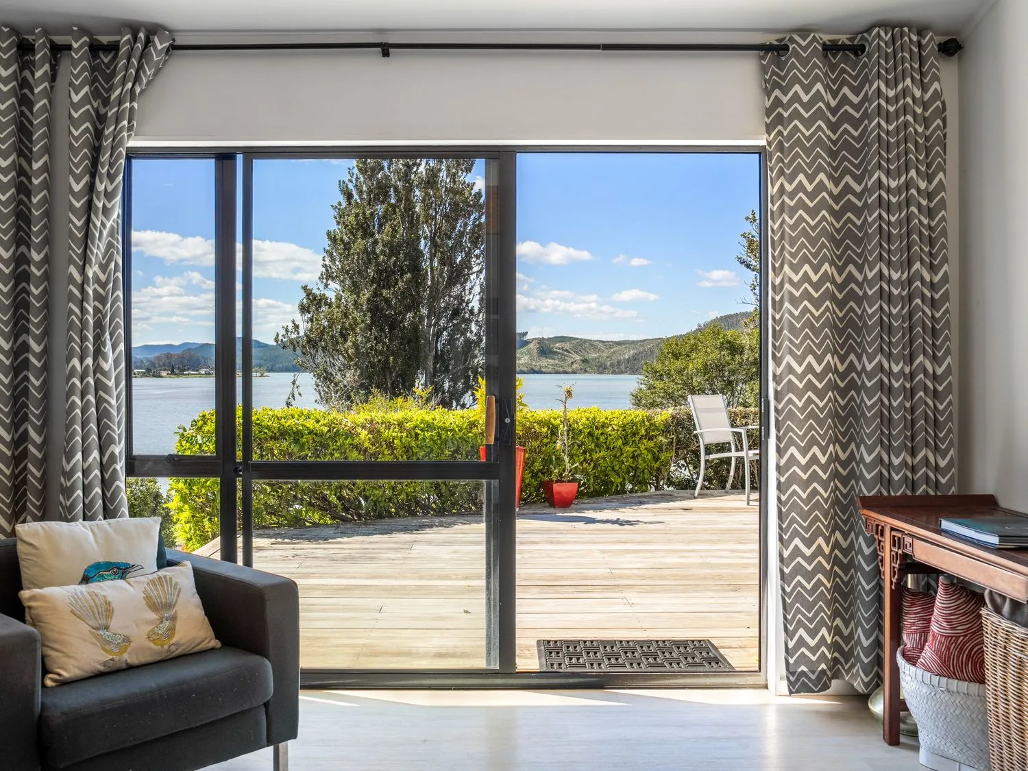 A living room with a view of the outdoors at Harbour house - Whangamata Holiday Home