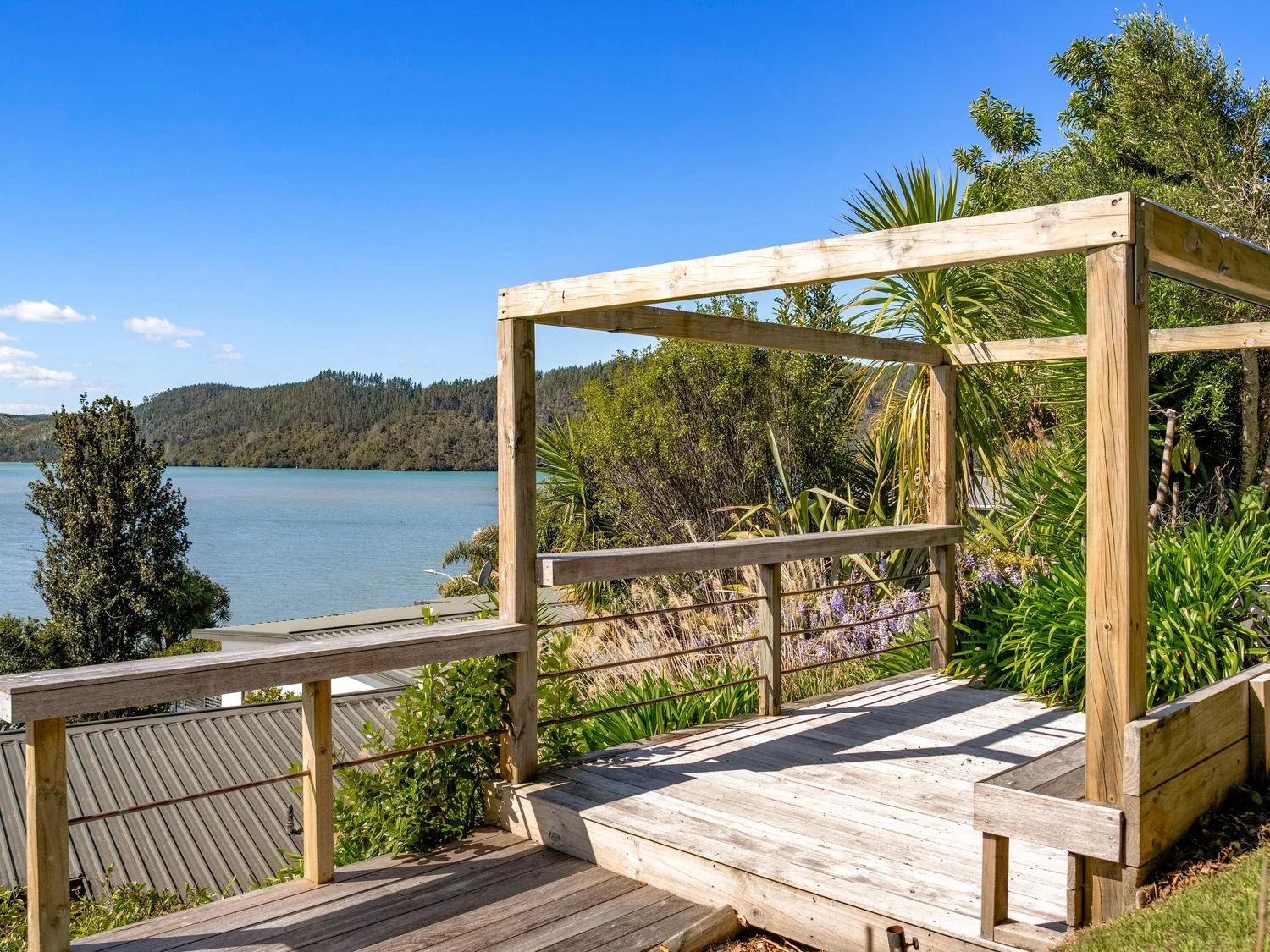 A deck overlooking water and trees at Harbour house - Whangamata Holiday Home