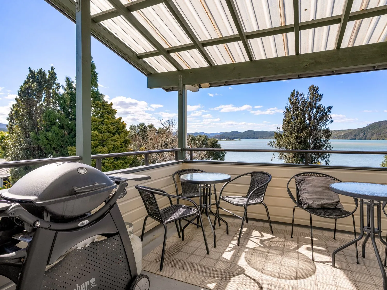 A balcony with a barbecue grill and seating at Harbour house - Whangamata Holiday Home