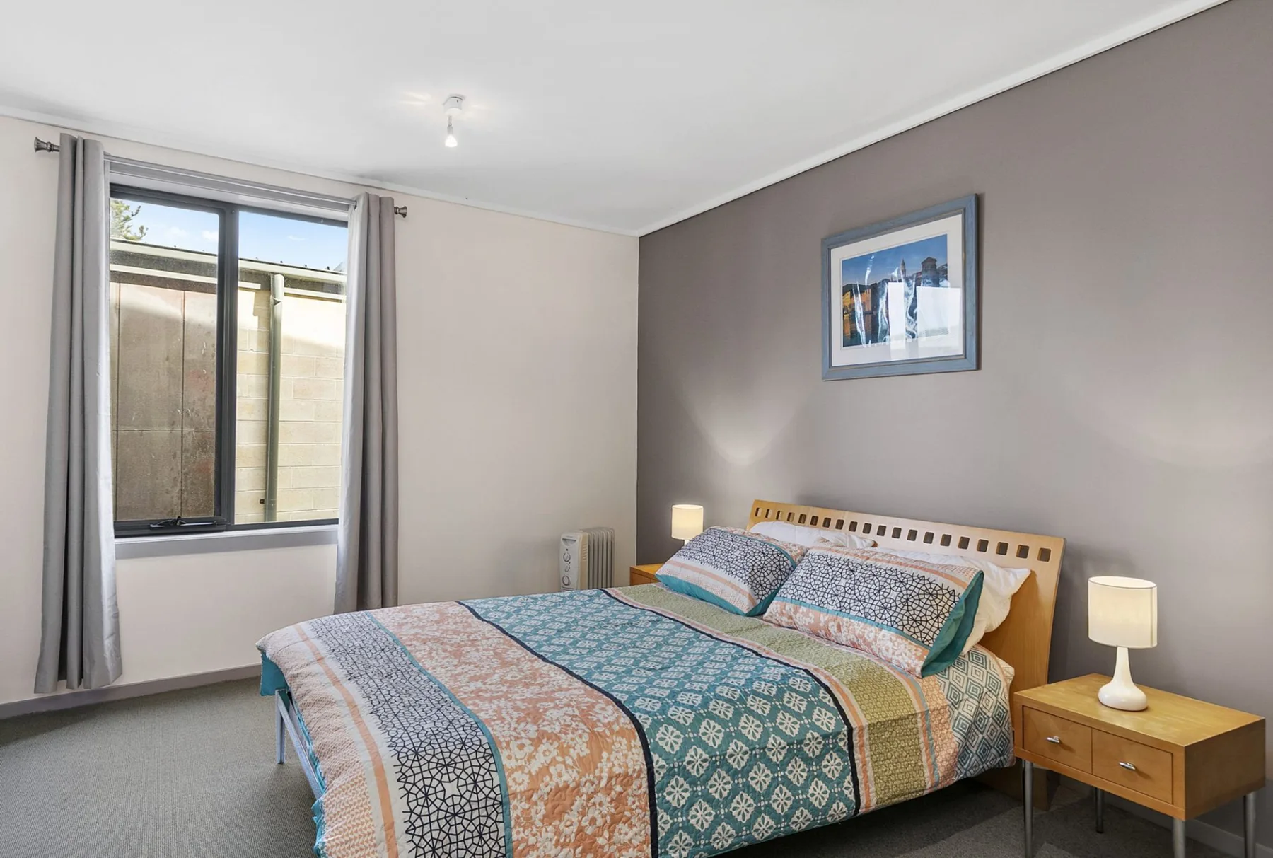 Un dormitorio con una cama cubierta con ropa de cama estampada y una ventana con cortinas.