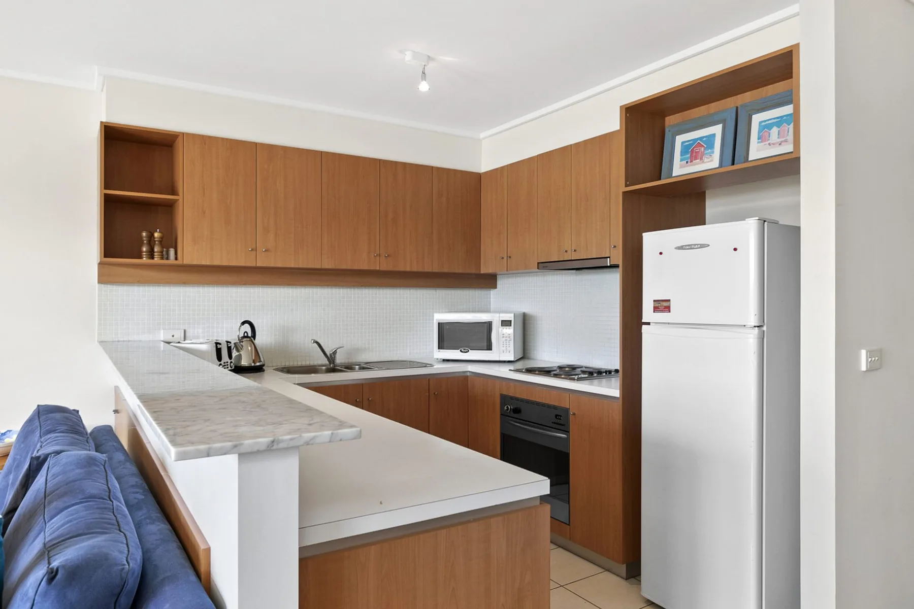Una cocina compacta con gabinetes de madera, una encimera y un refrigerador.