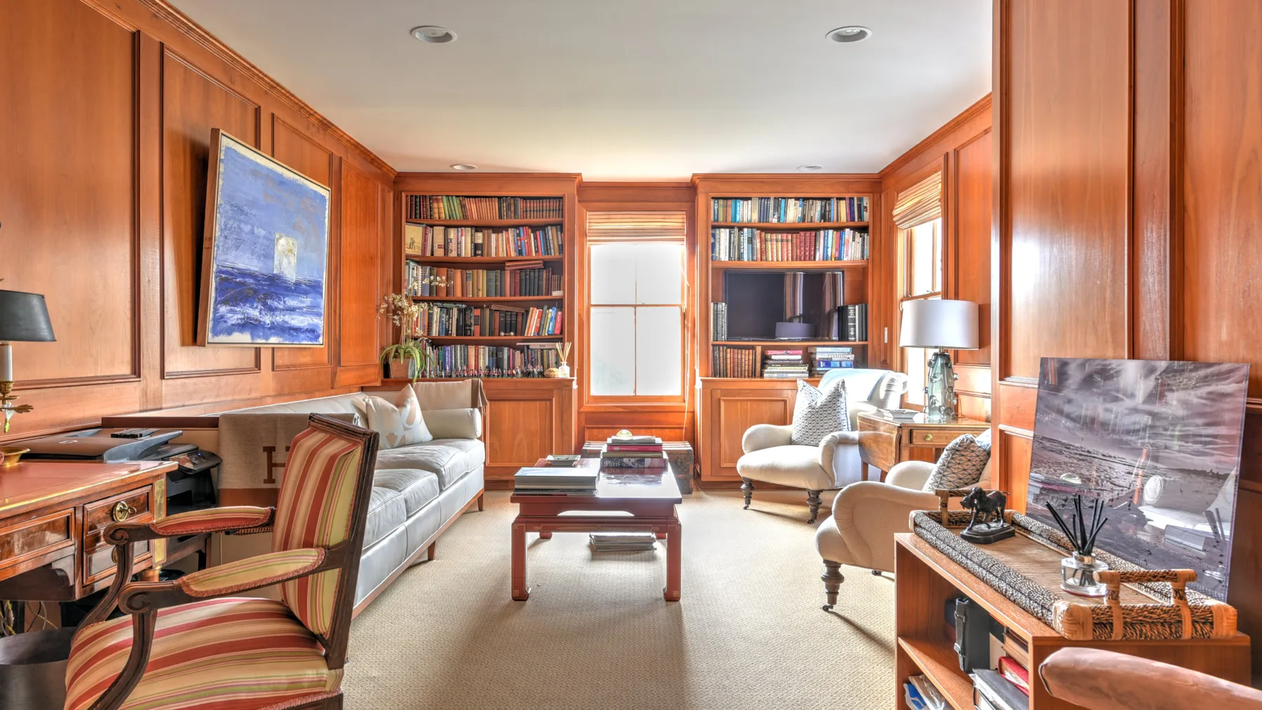 A wood-paneled living room with bookshelves, seating, and a coffee table.