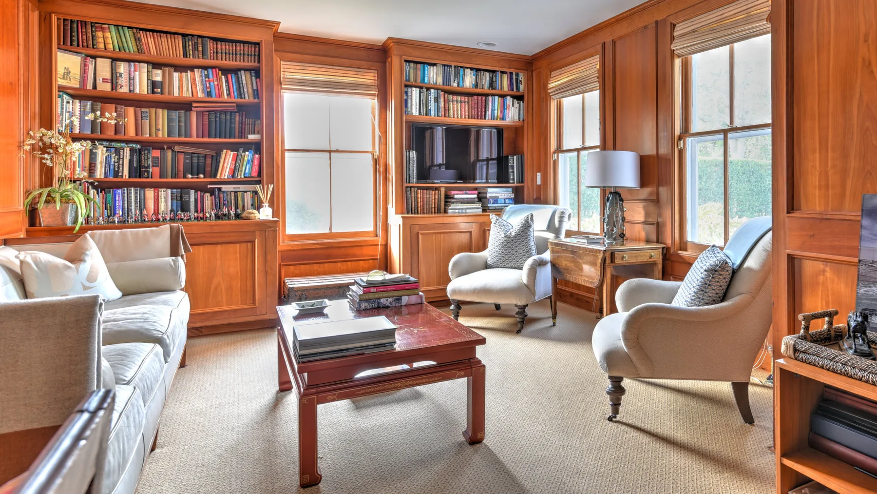 A wood-paneled living room with bookshelves, seating, and a coffee table.