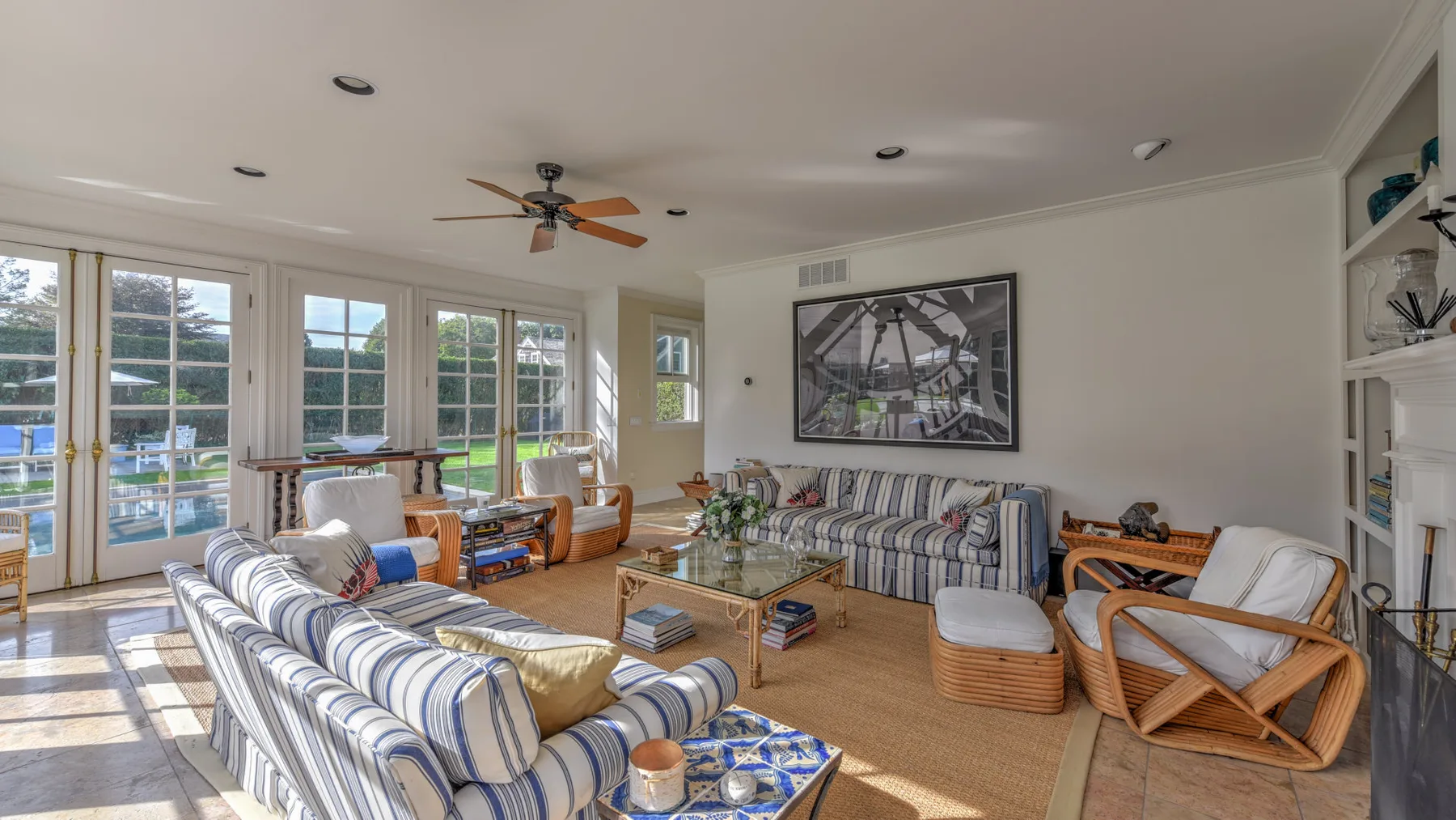 A bright living room with striped seating arranged around a glass coffee table.