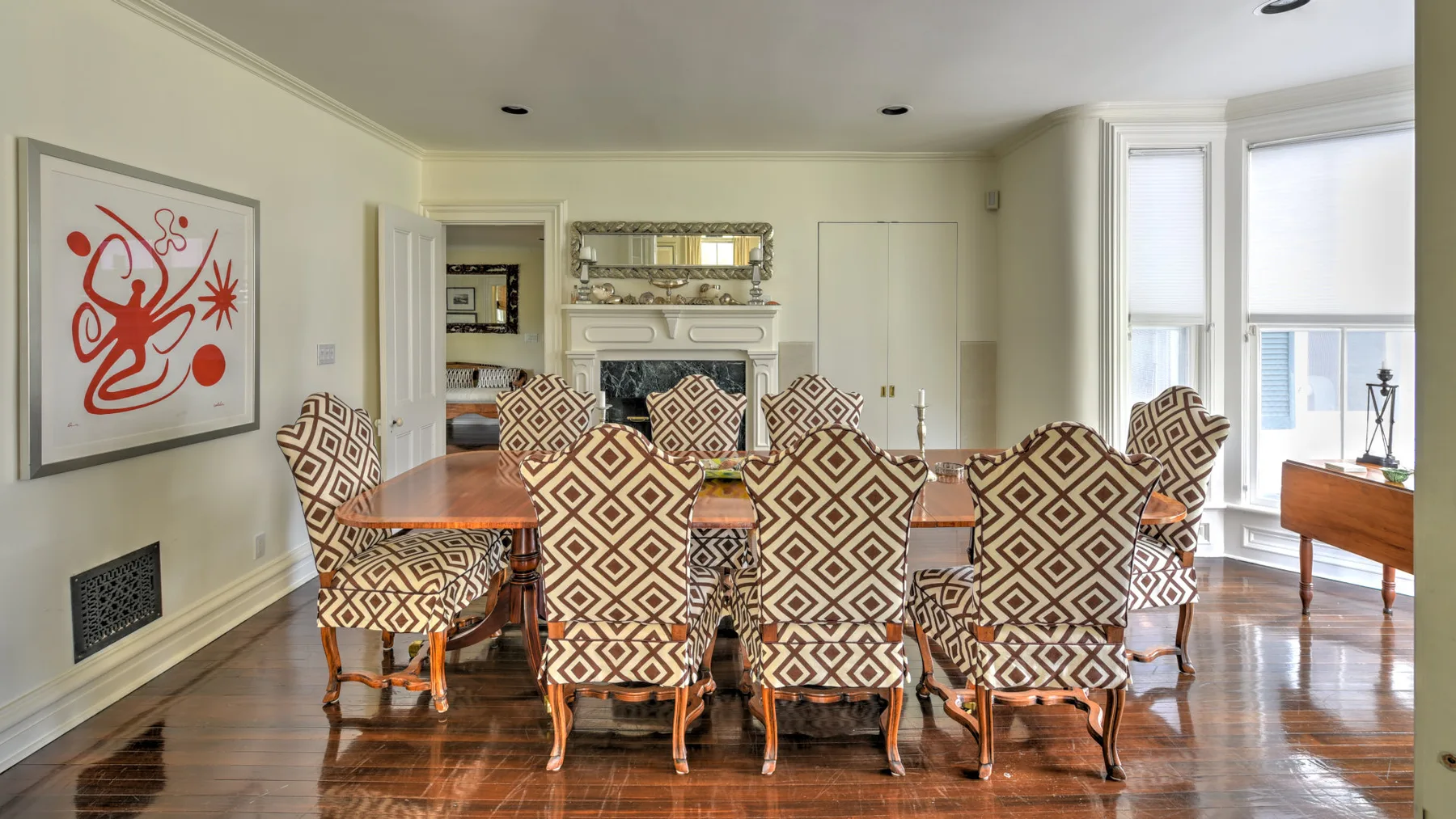 A dining room with a long table surrounded by patterned seating.