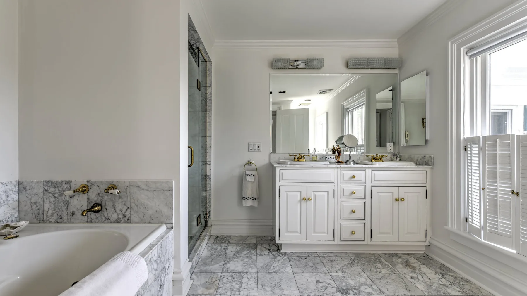 A bright bathroom with a bathtub, vanity, and large window.