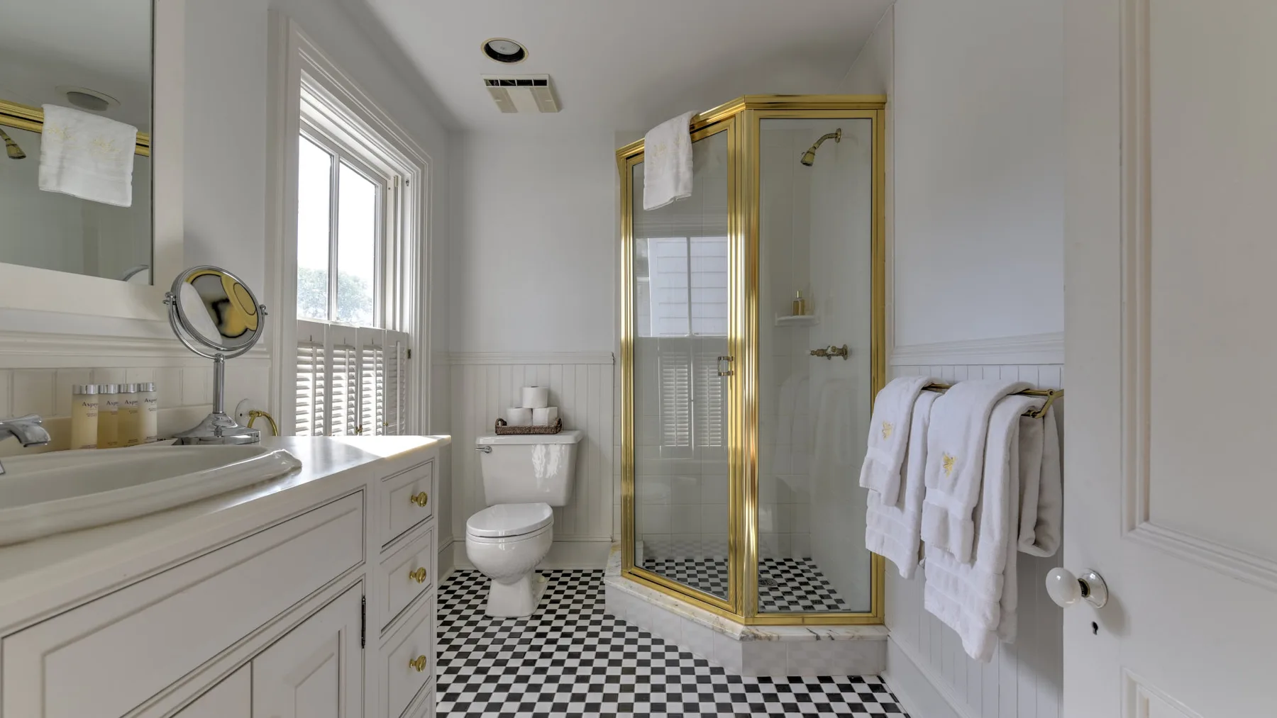 A bright bathroom with a checkered floor and glass shower.