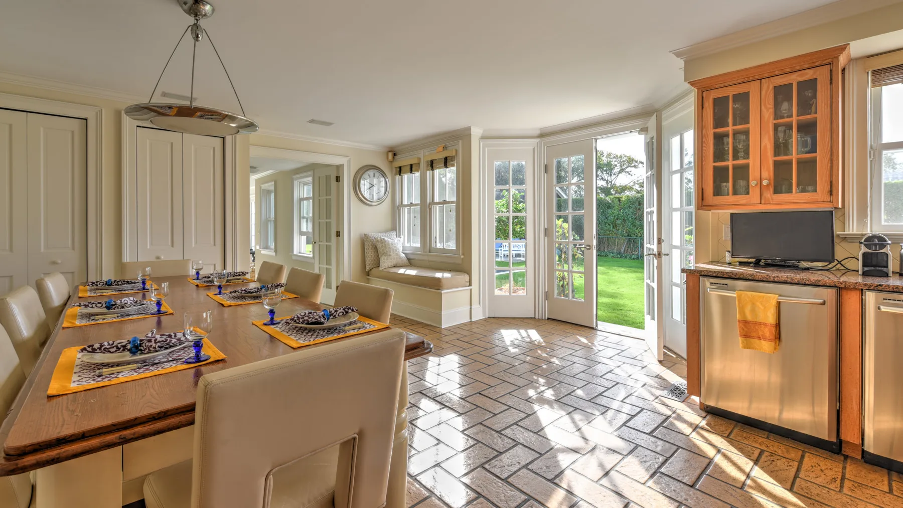 A bright kitchen and dining area opens onto a garden through glass doors.