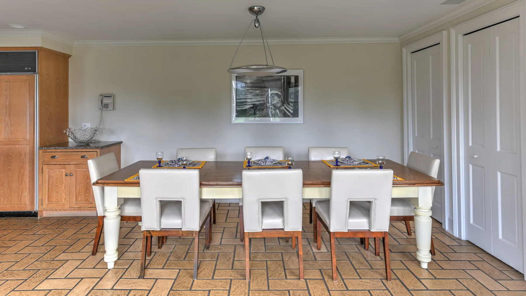 A dining room with a long table, chairs, and a pendant light.