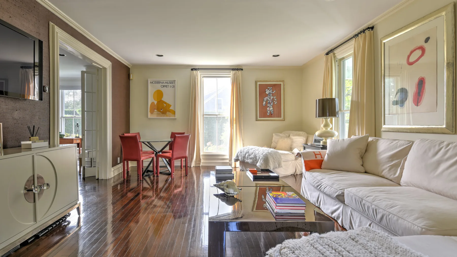 A living room with seating, a glass coffee table, and a dining area.