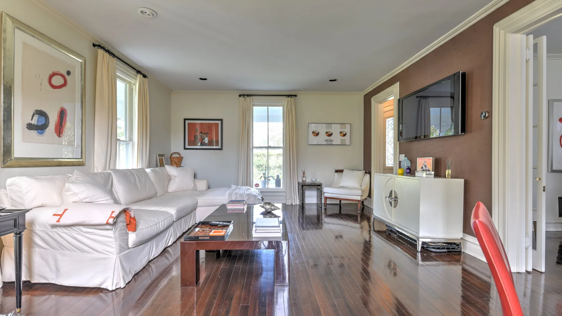 A living room with white seating, a coffee table, and a television.