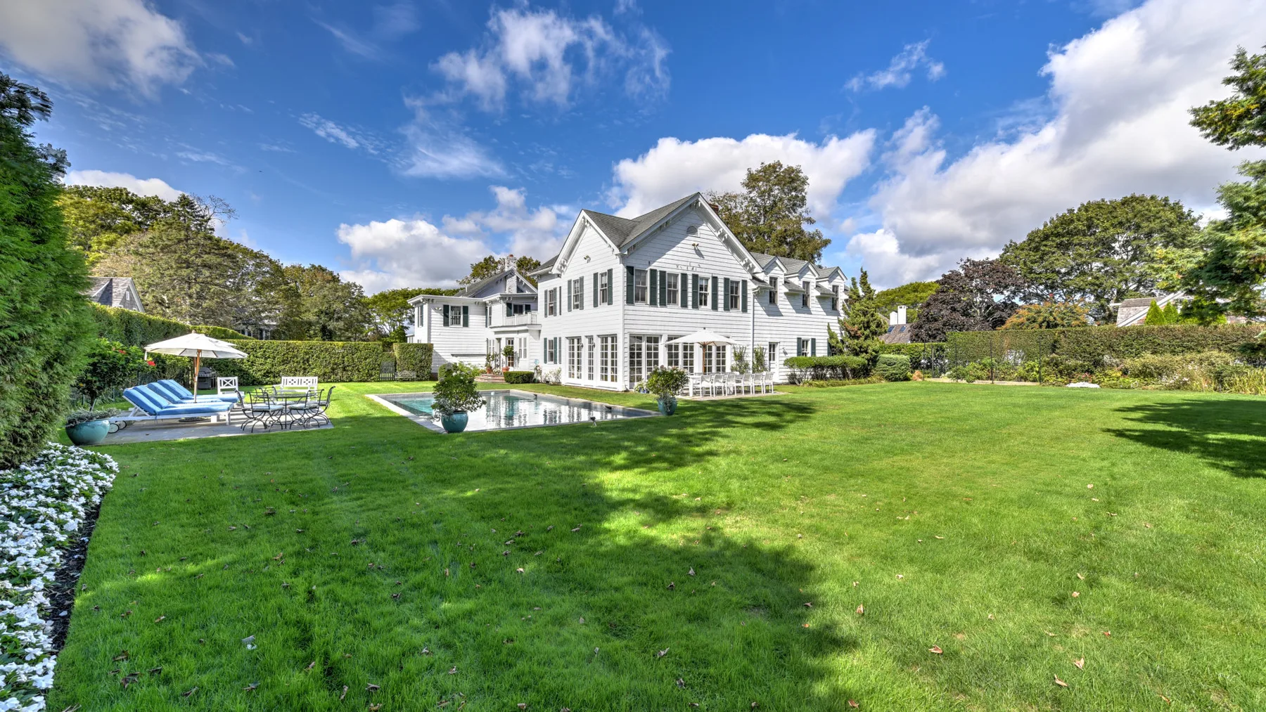 A large white house stands beyond a broad green lawn.