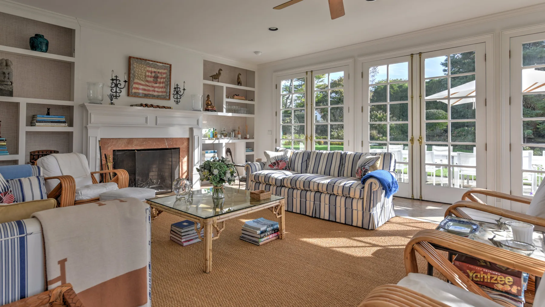 A bright living room with striped seating, a fireplace, and large windows.