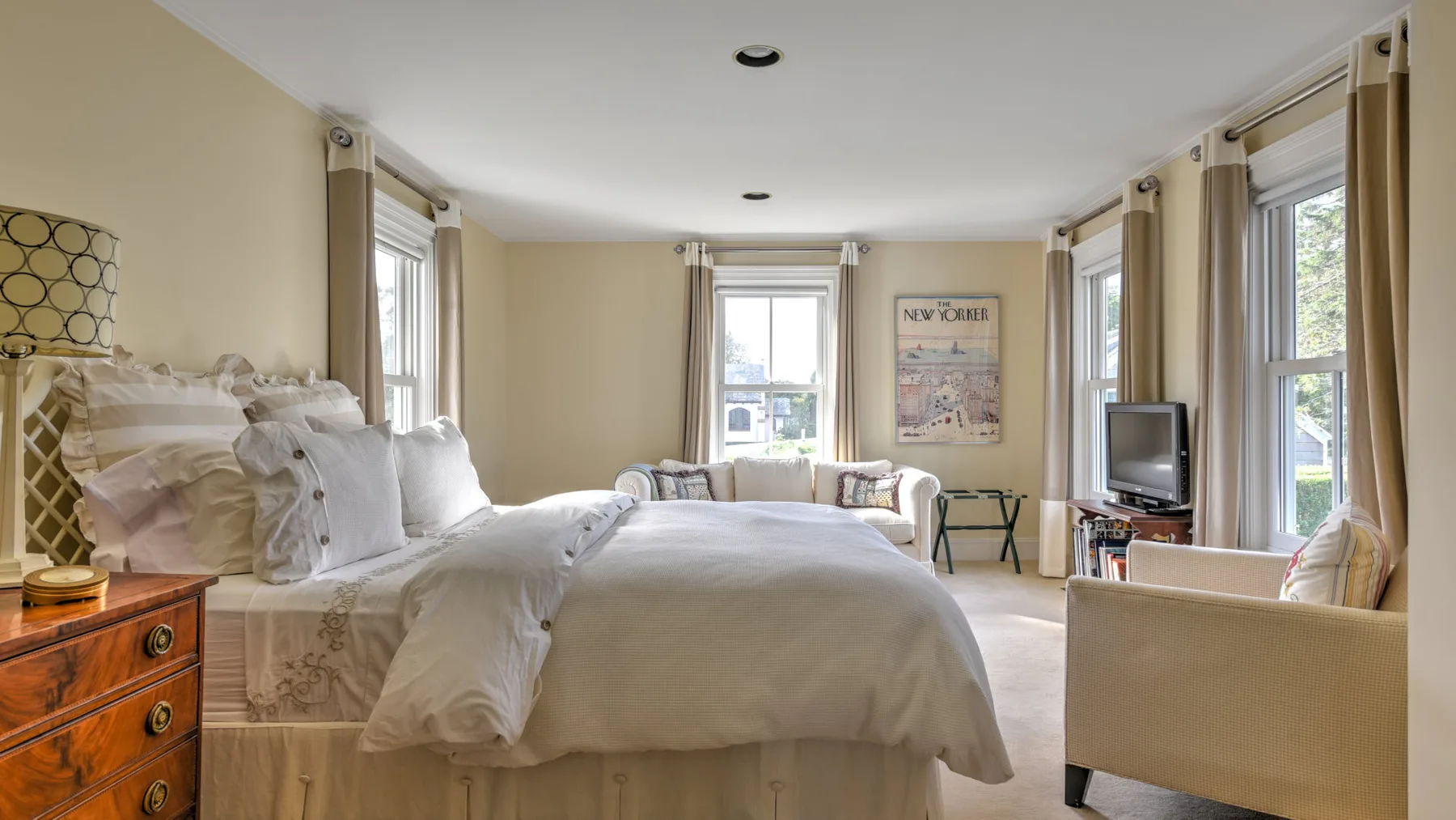 A bright bedroom with a neatly made bed and large windows.