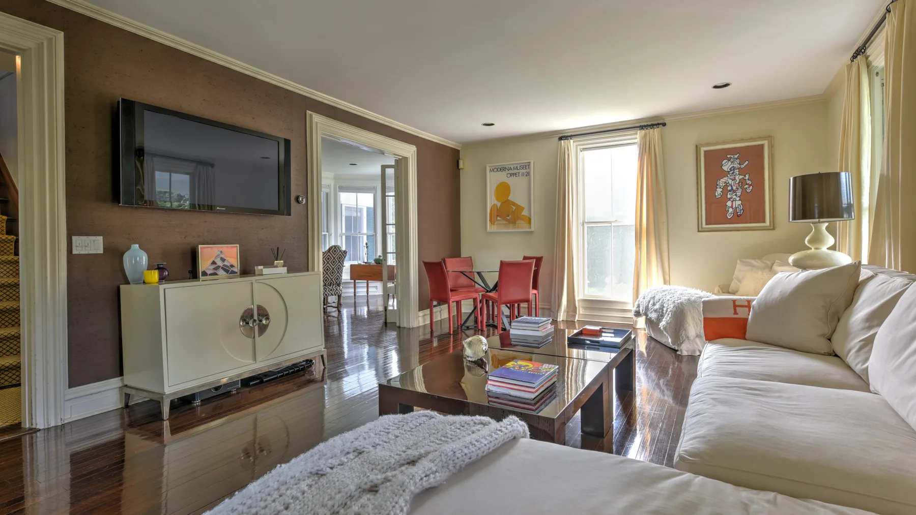 A living room with a white sofa and a coffee table beside tall windows.