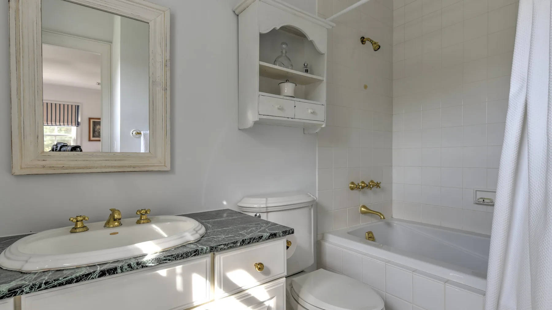 A bathroom with a sink, mirror, toilet, and bathtub.
