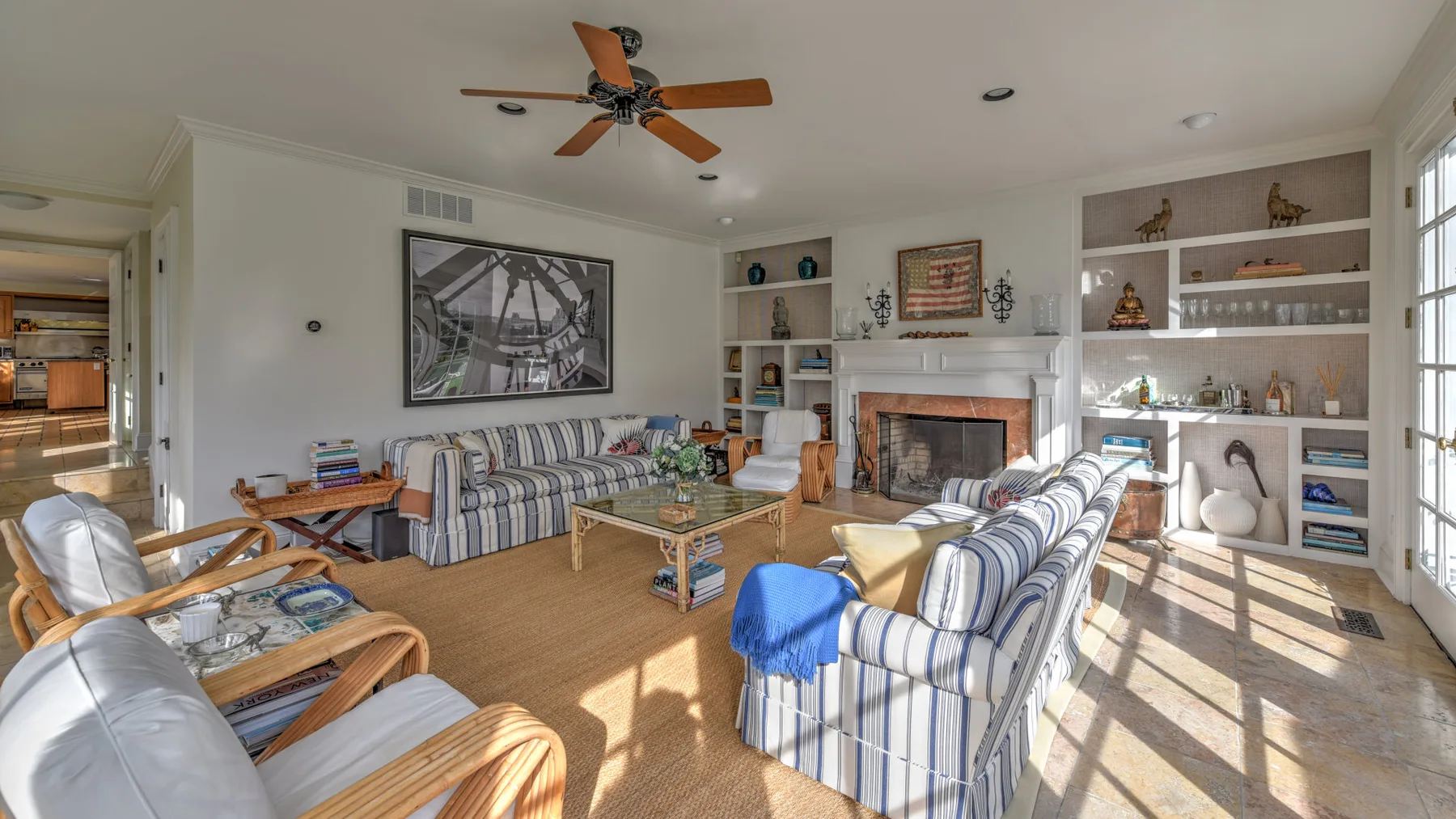 A bright living room with striped seating, a fireplace, and built-in shelves.