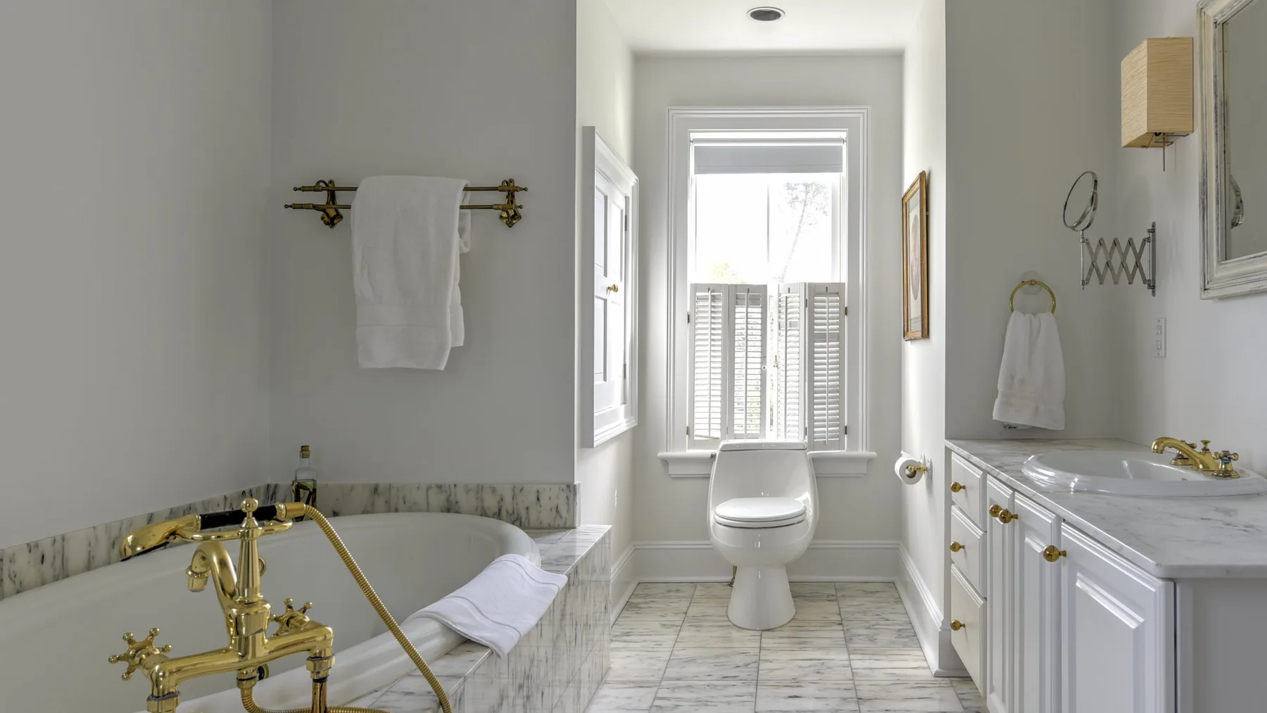 A bathroom with a bathtub, toilet, and sink beneath a bright window.