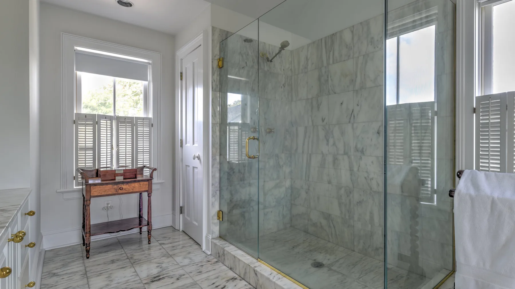 A bright bathroom with a glass shower and a window.