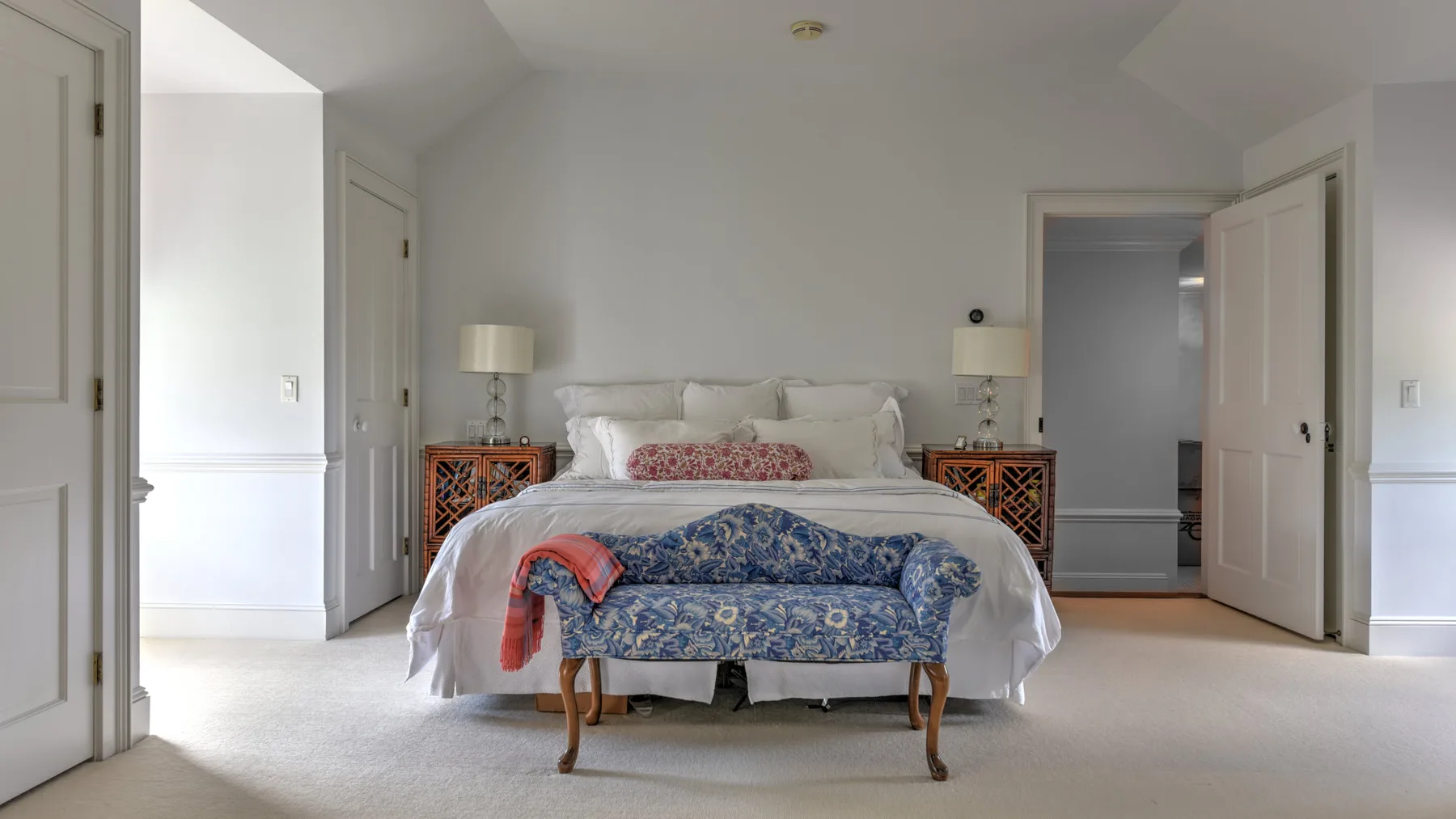 A bedroom with a bed and a blue patterned bench at its foot.
