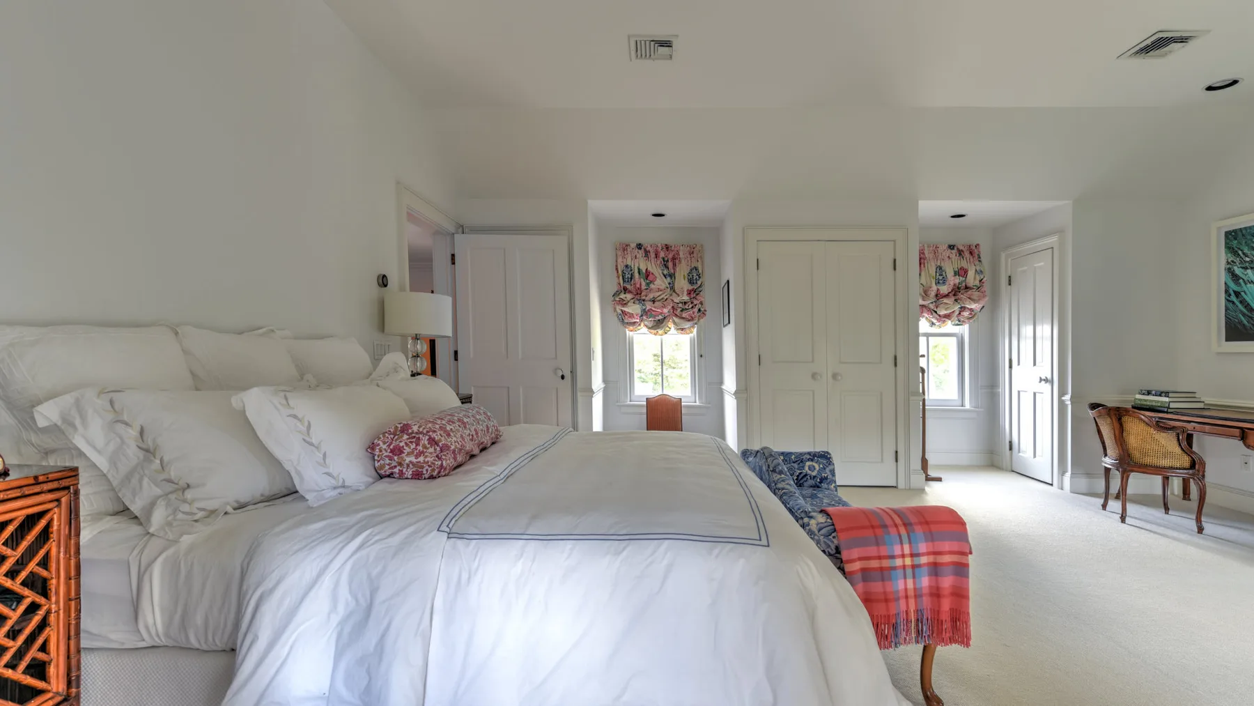 A bright bedroom with a neatly made bed and colorful window curtains.