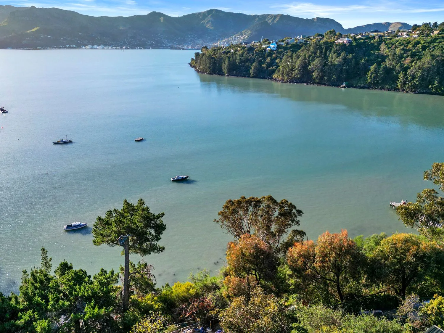 Una amplia bahía con pequeñas embarcaciones en aguas tranquilas y colinas arboladas al fondo.