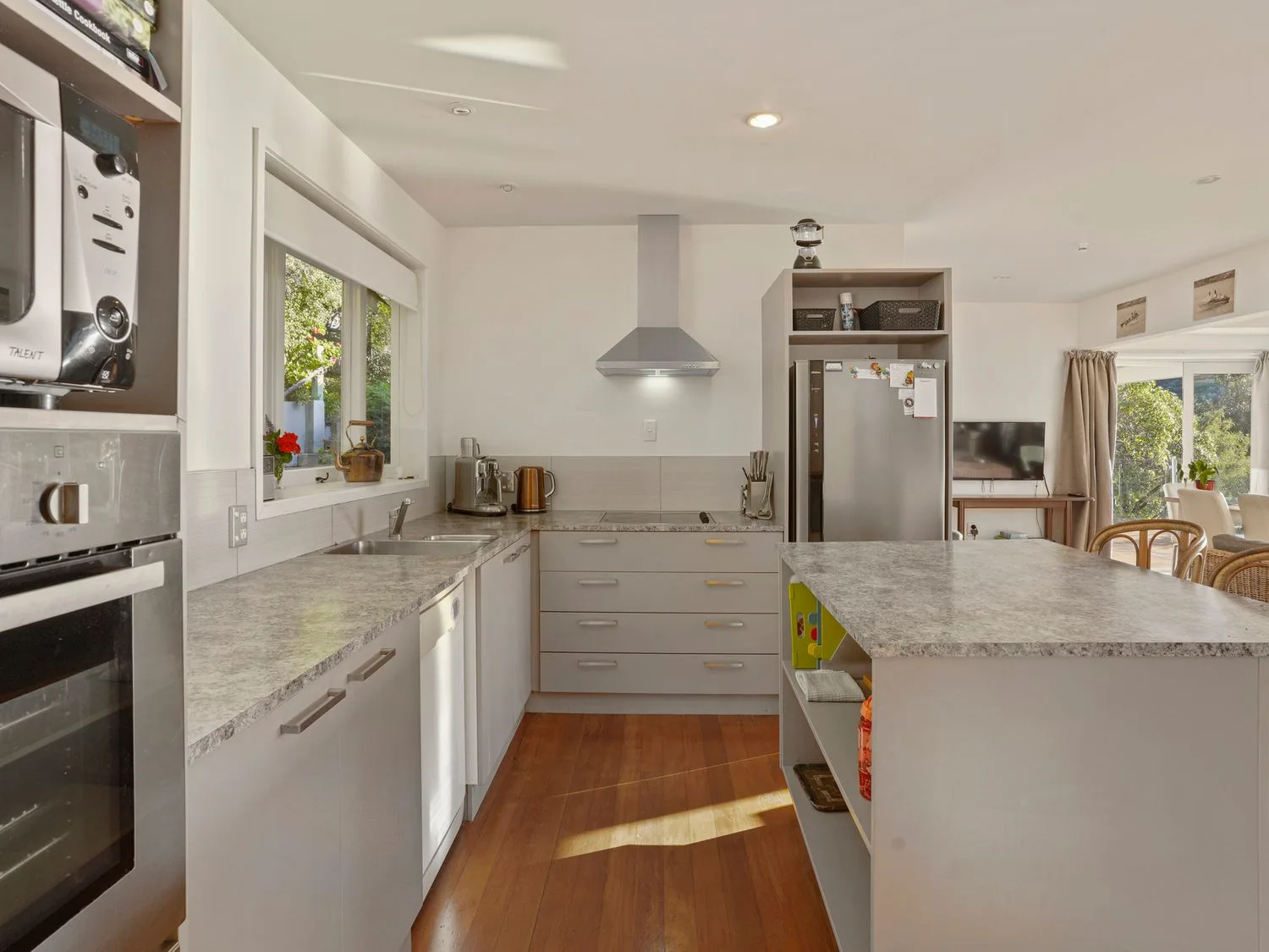 Una cocina con encimeras, armarios, un horno, un microondas, un refrigerador y una ventana con vistas en Kaioruru View - Diamond Harbour Holiday Home, en Diamond Harbour