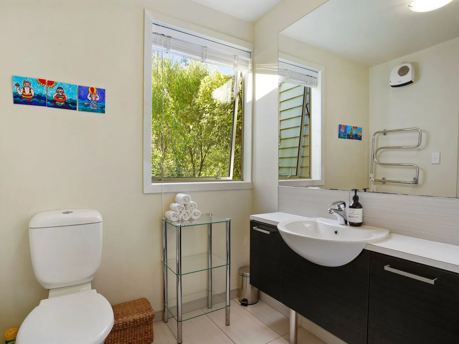 Un baño con inodoro, lavabo y una ventana con vistas a la vegetación.