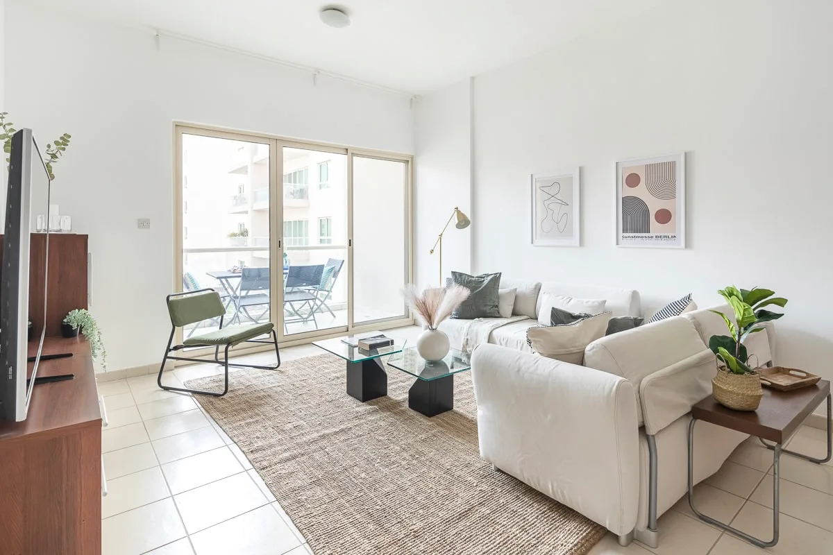 A bright living room with seating, a glass coffee table, and sliding doors to a balcony.