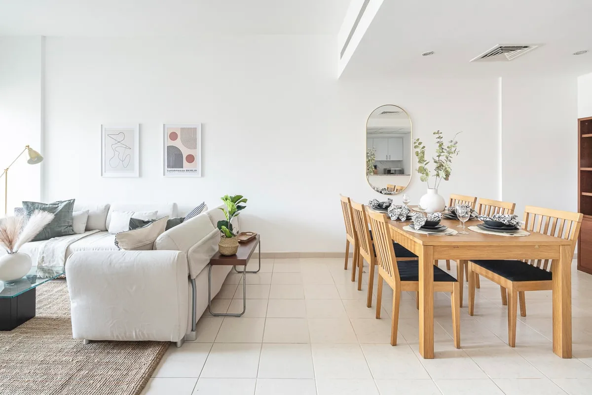 A bright living and dining area with seating, a dining table, and framed wall art.