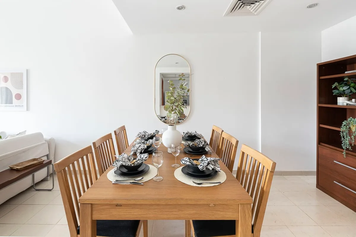 A dining room with a wooden table set for a meal and matching seating.