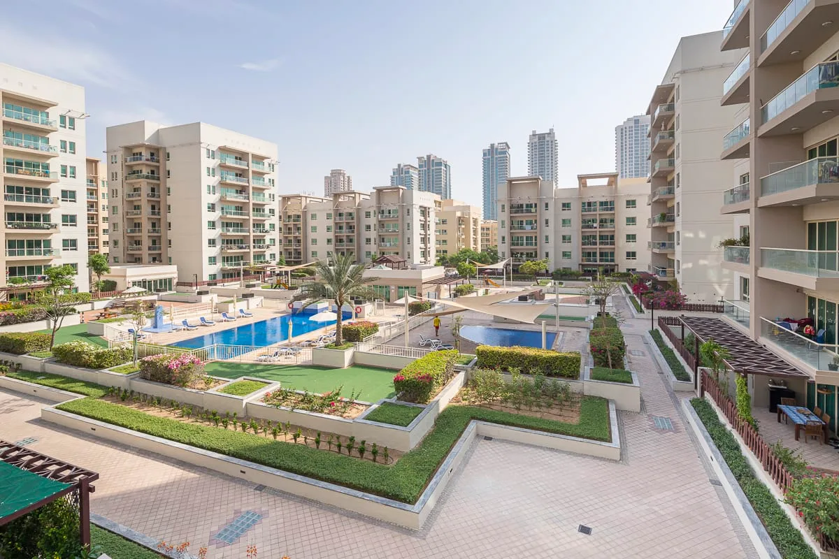 Apartment buildings surround landscaped courtyards with swimming pools and paved walkways.