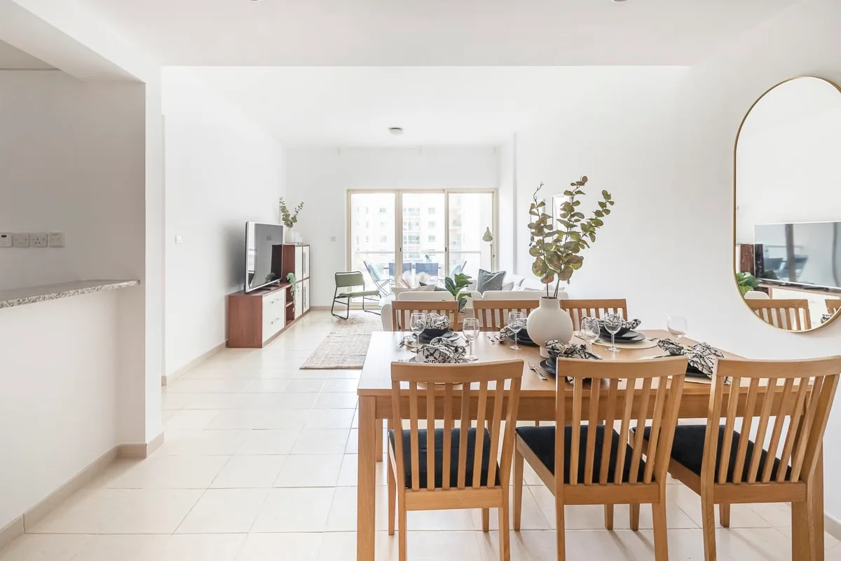 A bright dining and living area with a set table and seating near large windows.
