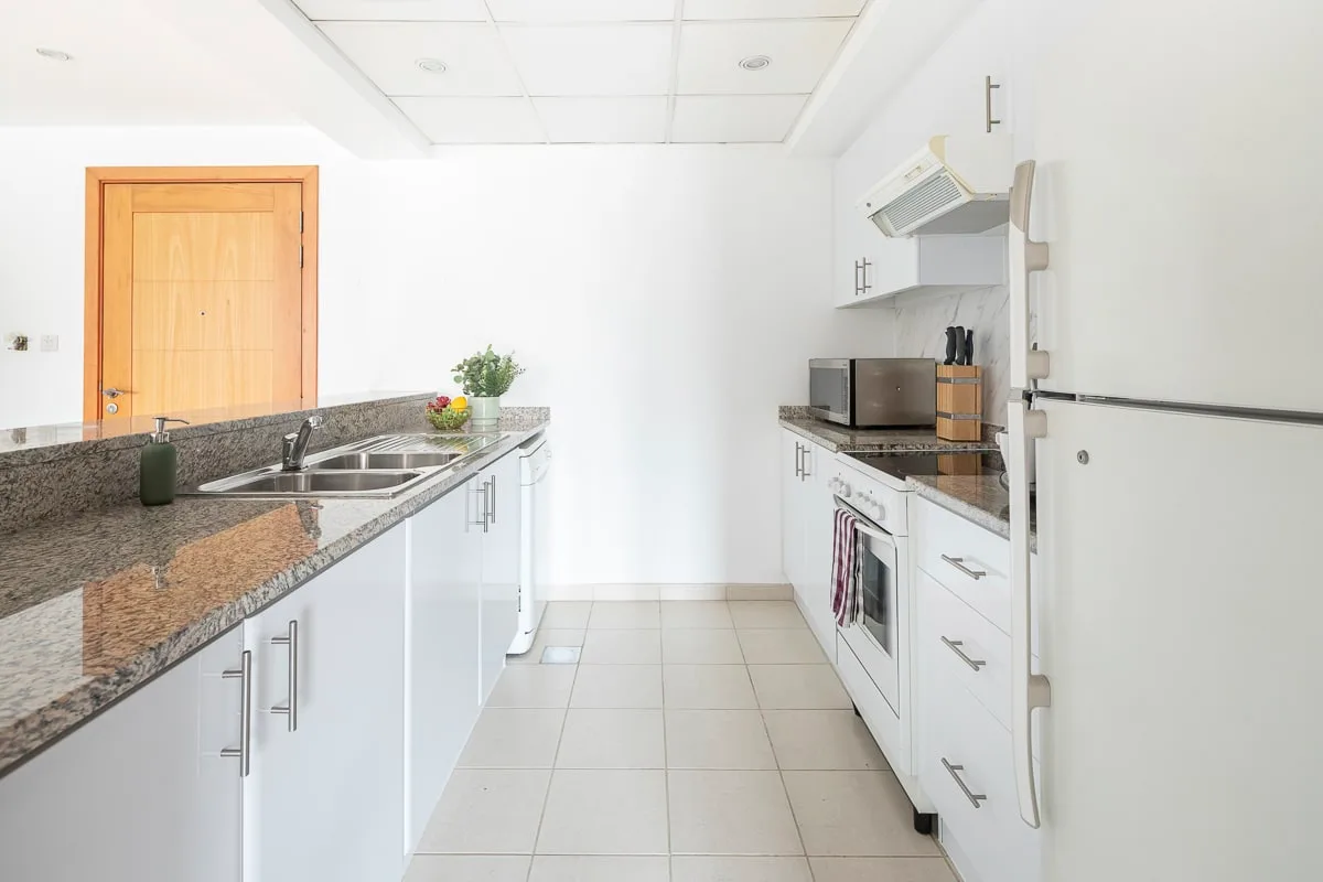 A bright kitchen with counters, a sink, and white cabinets.